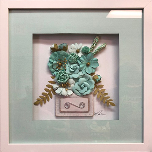Flowers of paper and fabrick in a white frame