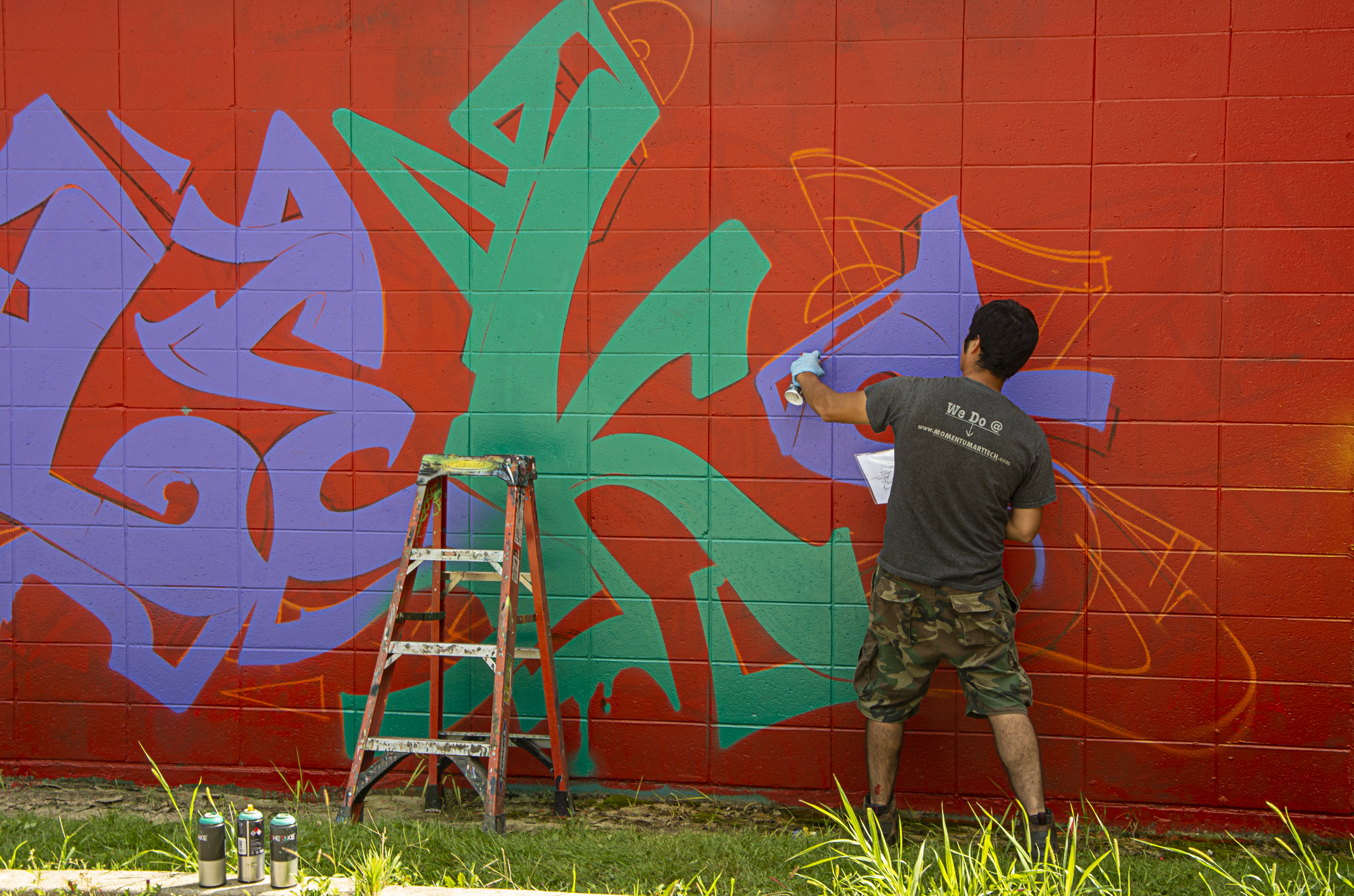 Street artist painting a wall.