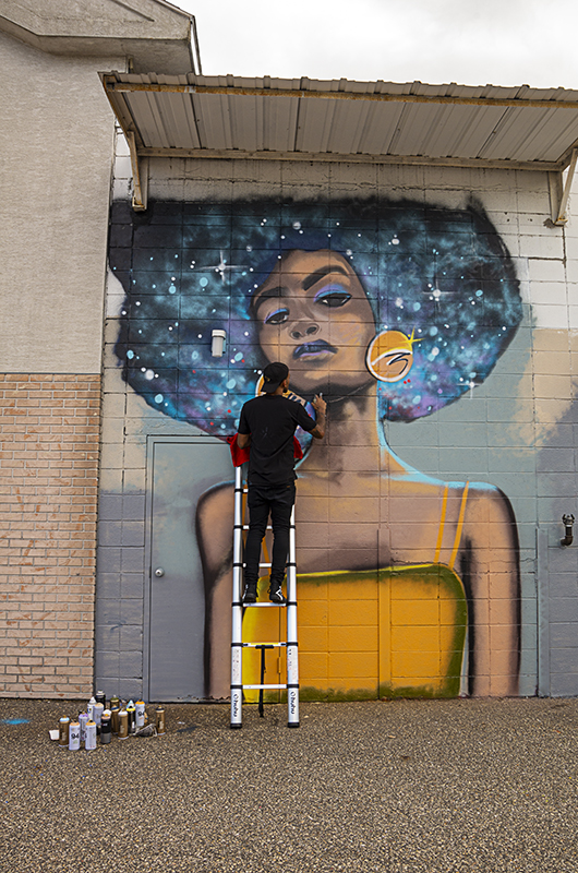 Man on a ladder painting a wall.